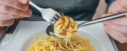 Hands of man eating spaghetti with worms