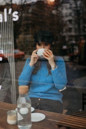 stylish woman drinking coffee into a coffee shop looking away