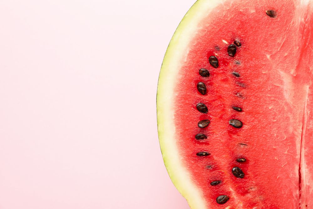 Half of fresh watermelon on pink background. Summer fruit