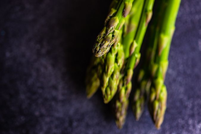 Tips of raw asparagus on dark counter