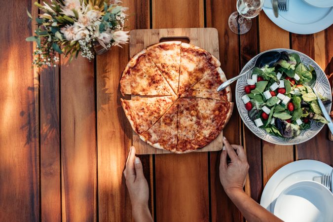 Top view of female hands setting food and pizza on the table for a party