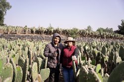 Mother and son are posing in a nopal field while working during the harvest