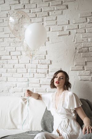 Charming young woman with red lips in white dress smiling at camera