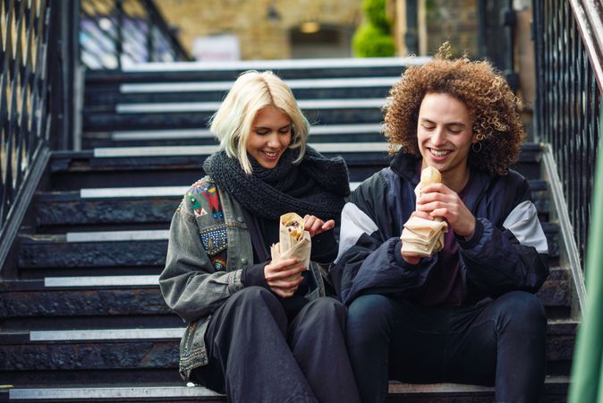 Couple eating sandwich on stairs