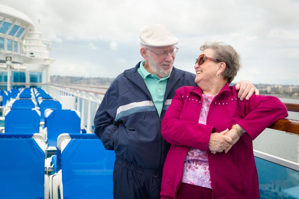 Grey Haired Adult Couple Enjoying The View From Their Passenger Cruise Ship Railing.