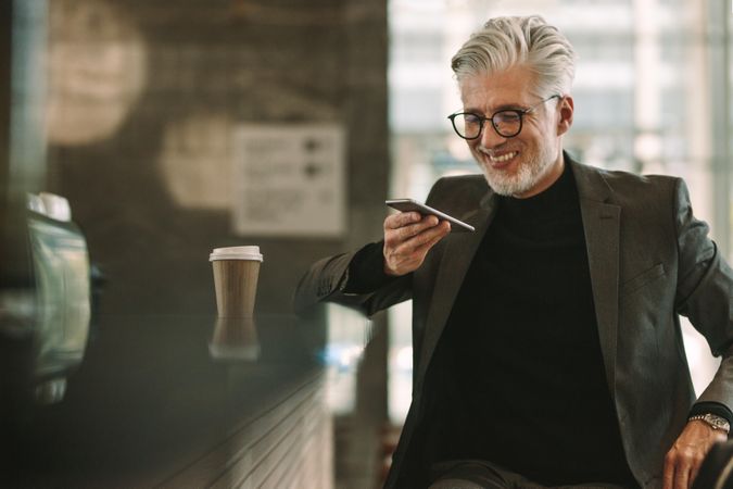 Portrait of happy mature businessman at cafe making phone call