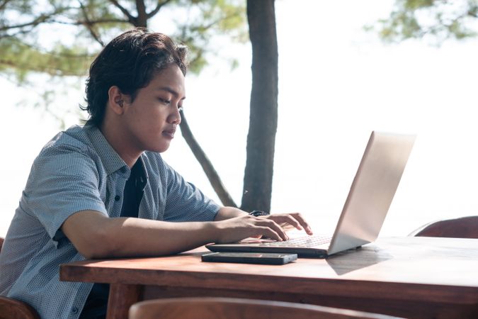 Serious Asian Young businessman work at outdoor with laptop. Concept of remote and freelance work. Young successful man wearing casual blue cloth.
