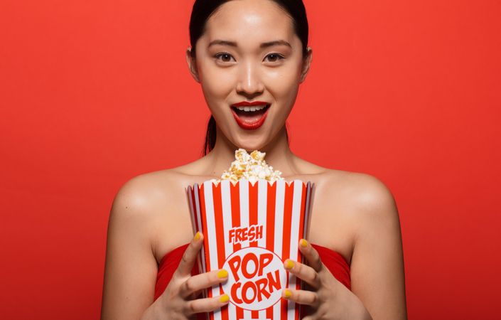 Excited woman holding popcorn bucket