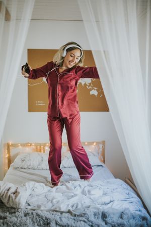 Woman with headphones dancing in bed