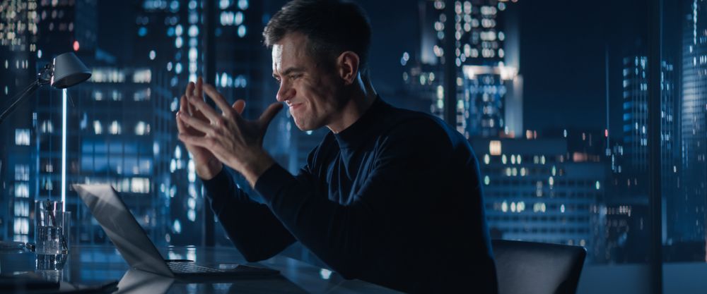 Successful Businessman Working on Laptop Computer in Big City Office Late At Night.