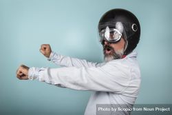 Side view of man with helmet and glasses pretending to ride a motorcycle in studio 56EvL0
