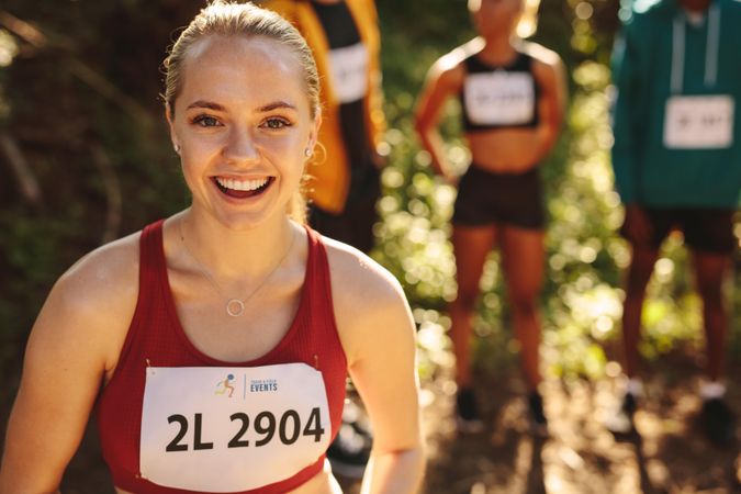 Woman runner standing outdoors looking at camera and smiling