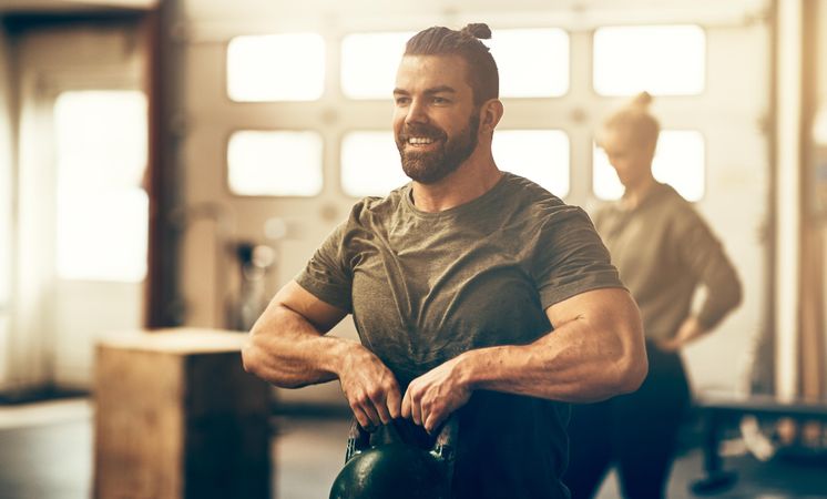 Man lifting kettlebell to chest in gym