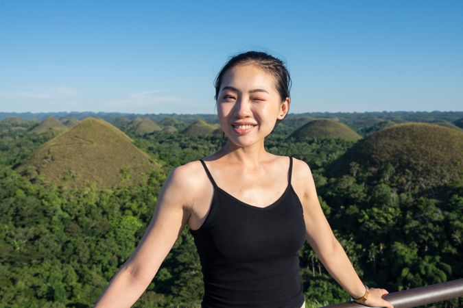 Happy woman standing on observation deck on hill