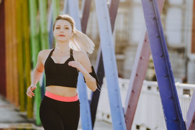 Woman with earphones running on street