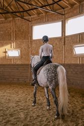 Rider riding dapple gray horse in round arena