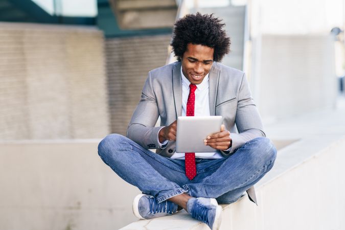 Calm man using digital tablet sitting cross legged