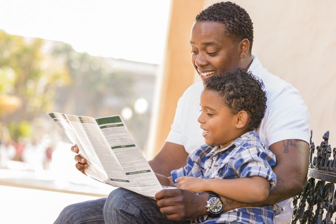 Father and Son Reading Brochure Outside