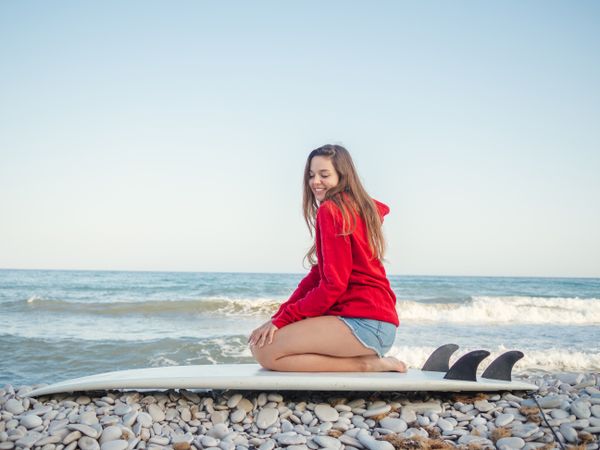 Cheerful woman sitting on surfboard