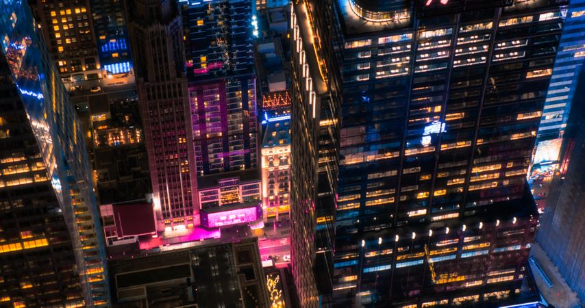 Helicopter Tour of New York Cityscape at Night. Manhattan Offices with Lights and Congested Streets with Cars and Taxi Vehicles in a Big City. Building with Pink Neon Billboard