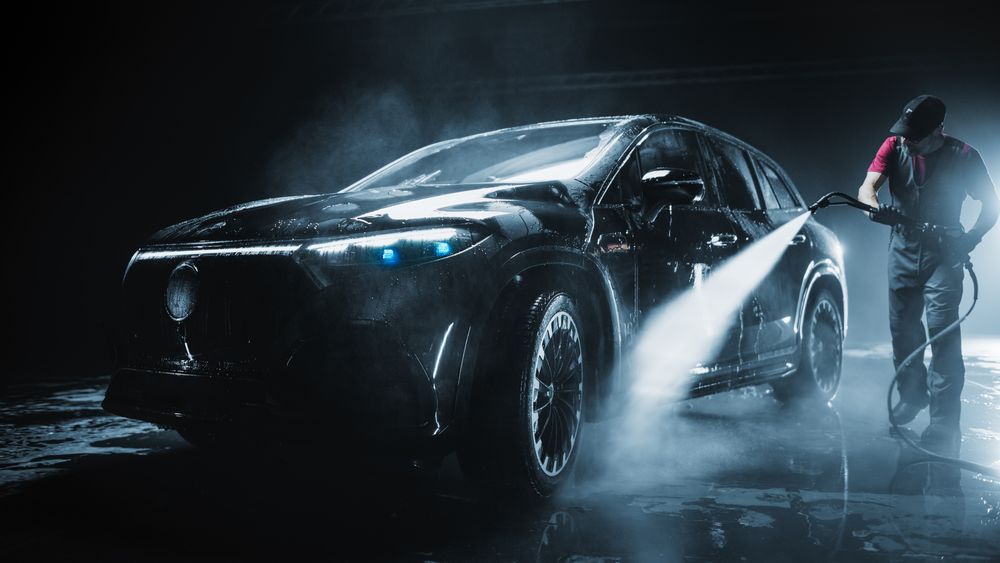 Brand New Electric Vehicle from a Production Line is Being Cleaned with a Water High Pressure Cleaner.