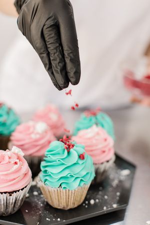 Person adding sprinkles to cupcakes