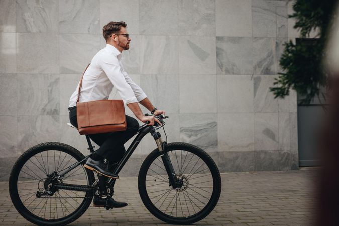Side view of a man wearing an office bag riding a bike