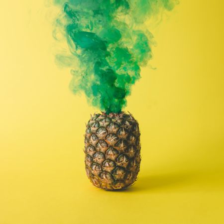 Pineapple with green smoke on bright yellow background