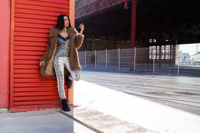Trendy woman with smartphone near wall