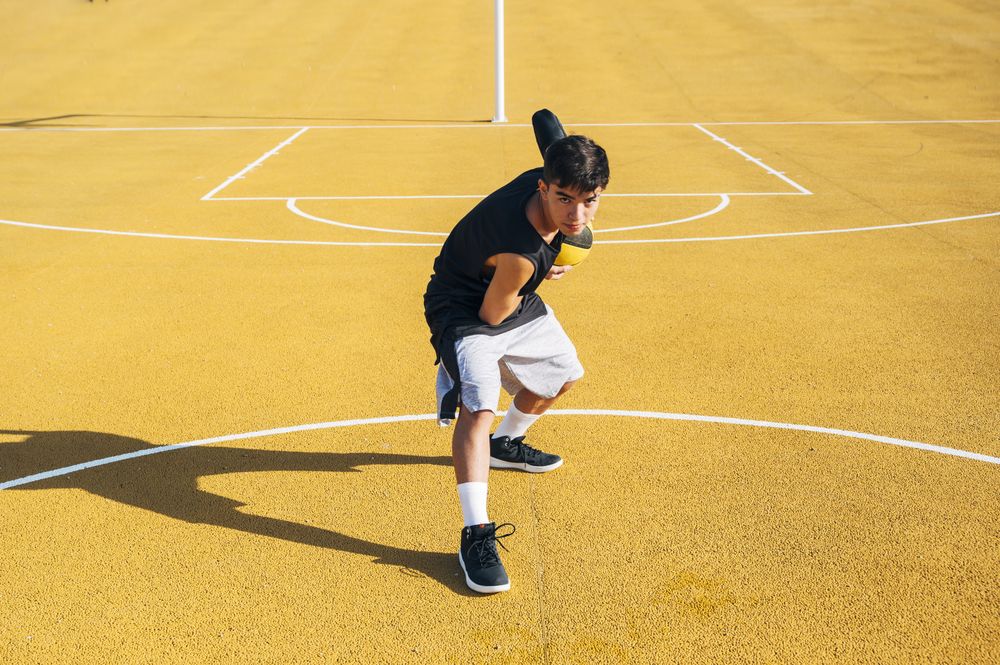 Young man playing on basketball court outdoor.