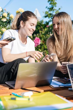 Young women smiling showing videos or news on their mobiles on a break from work outside the office.