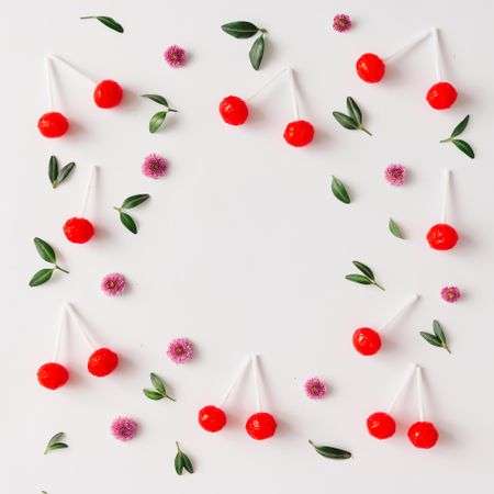 Colorful pattern made of red cherry lollipops, leaves, and flowers