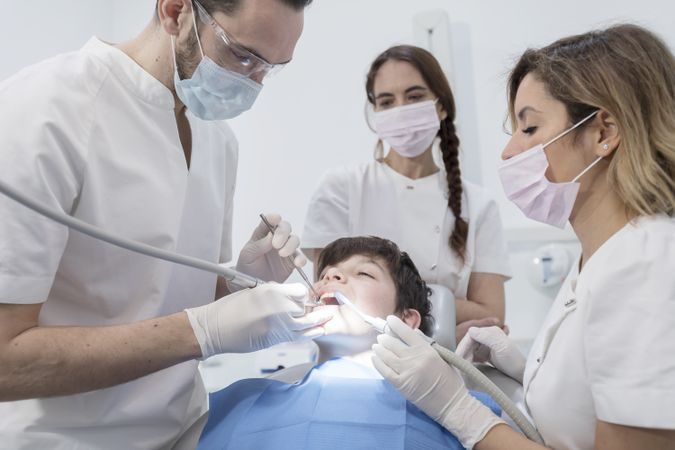 A portrait of dental team team working on young male patient