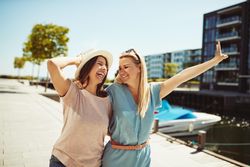 Two happy women walking along the river on a sunny day
