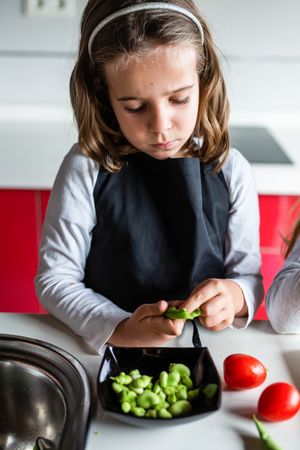 Young girl preparing vegetables for salad
