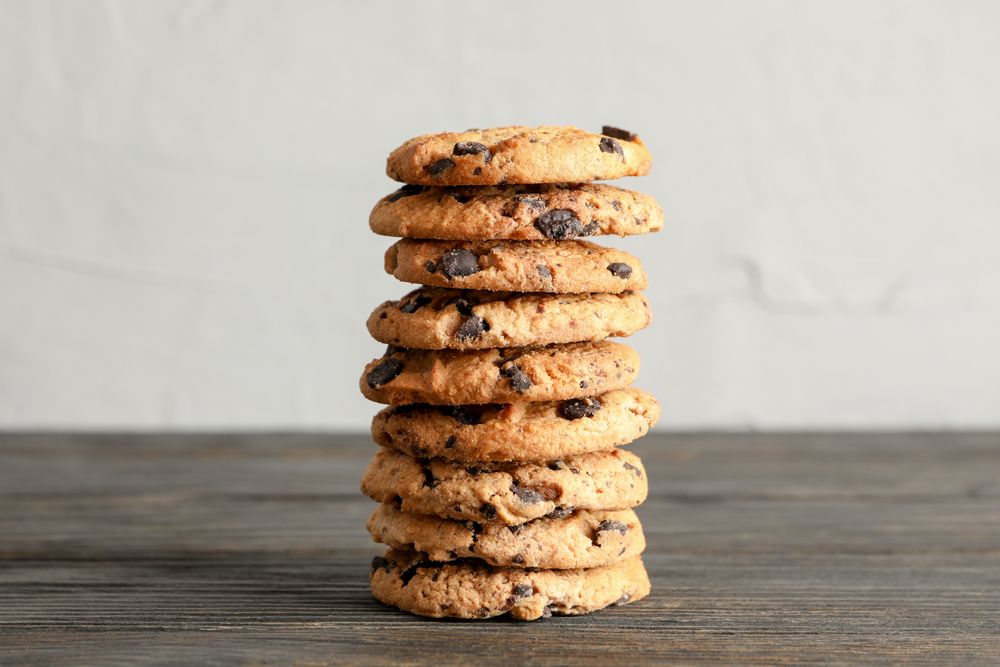 Stack of tasty chocolate chip cookies on wooden table. Space for text