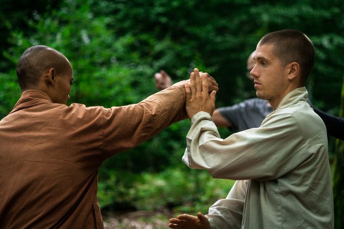 man training martial arts student in forest