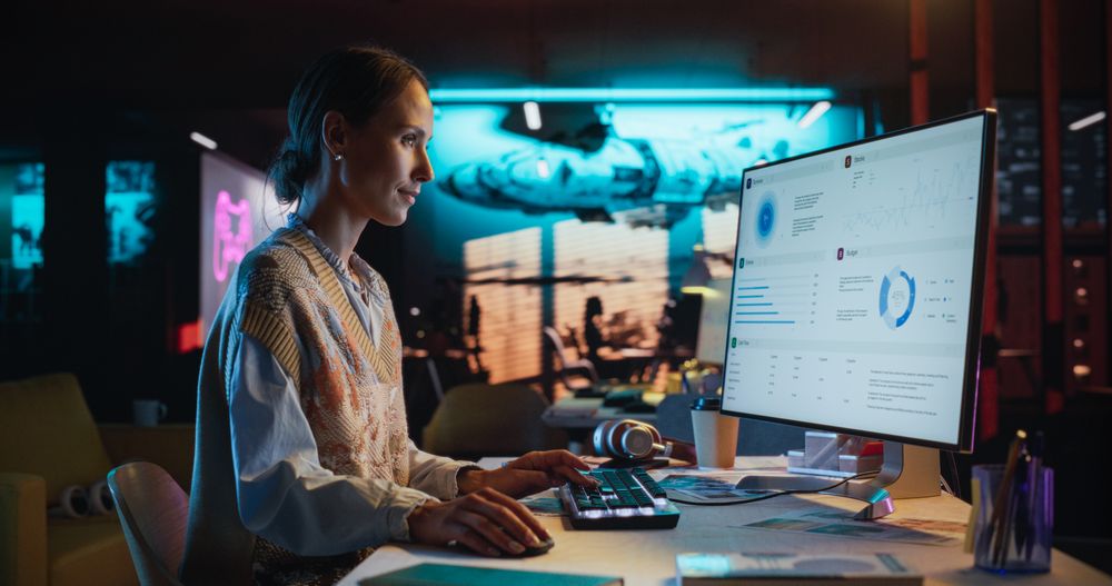 Female Digital Marketing Specialist Working on Computer at Office in the Evening.
