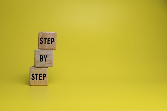 step by step word on wooden blocks staircase isolated on yellow background. concept of success progress or career