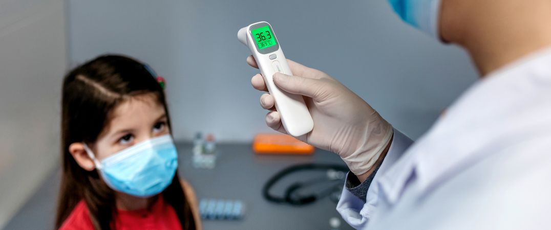 Female doctor looking at infrared thermometer after taking tempe