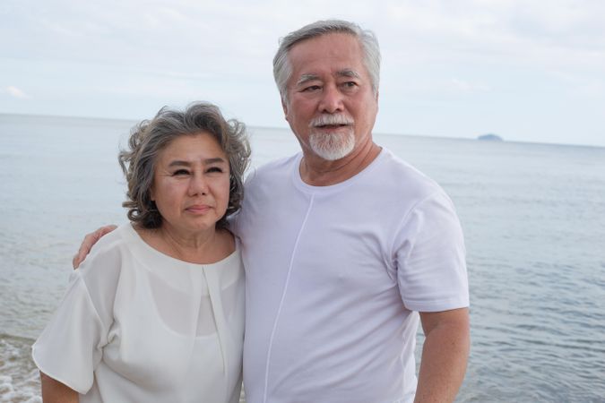 Mature Asian couple posing for photo at the beach