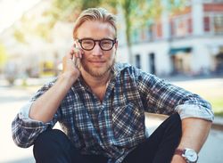 Man in glasses sitting while on his cellphone