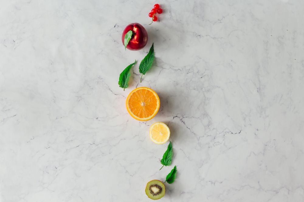 Fruits and herbs on bright marble table background