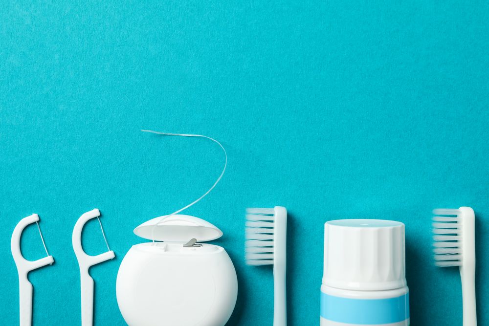 Tools for dental care on turquoise background, space for text