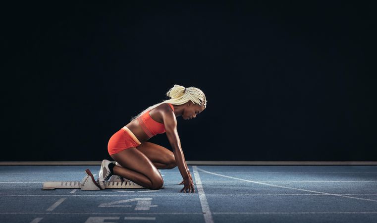 Female athlete taking position on her marks to start off the run