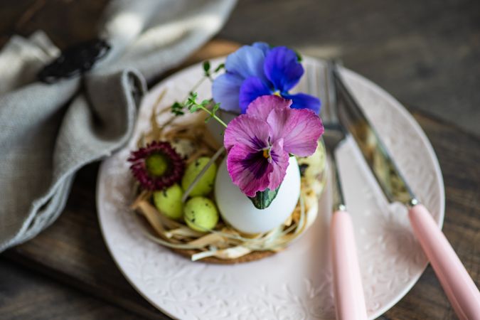Easter table setting with elegant pink plate, colorful flowers and decorative eggs