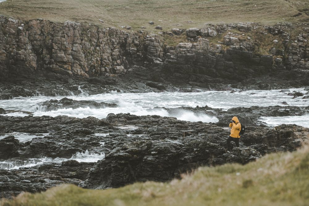 Man standing on rock and taking picture of sea