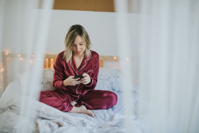 Woman sitting in bed with smartphone