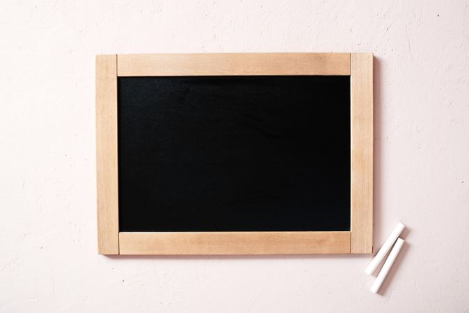 Blank chalkboard with two pieces of chalk