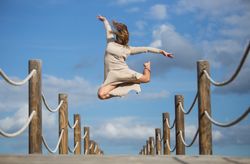Woman with textile posing in air on footbridge